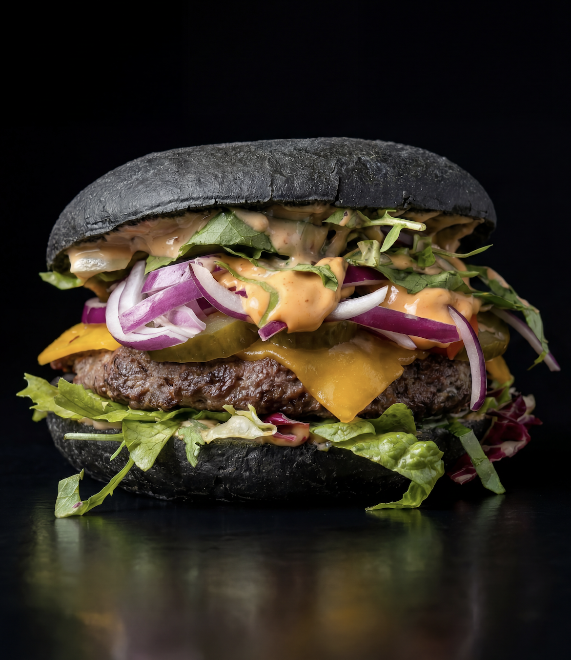Burger mit schwarzer Semmel, Cheddar und roten Zwiebeln